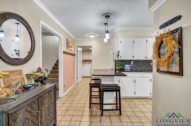 918 S Evenside St, Henderson, TX 75654 - kitchen with dark countertops, crown molding, white cabinets, washer / dryer, and light tile patterned floors