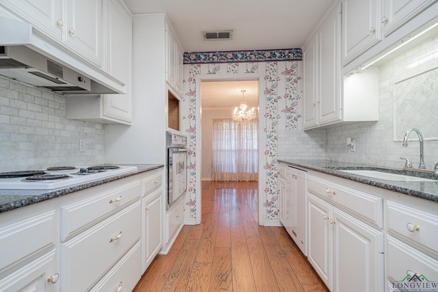 kitchen with dark stone counters, white appliances, sink, light hardwood / wood-style flooring, and white cabinetry