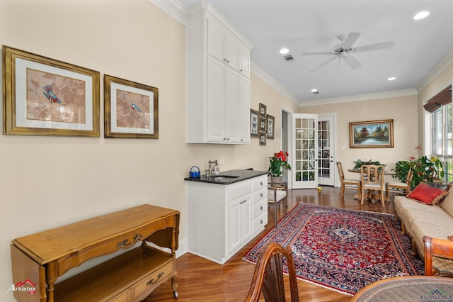 kitchen featuring white cabinetry, sink, ornamental molding, ceiling fan, and wood-type flooring