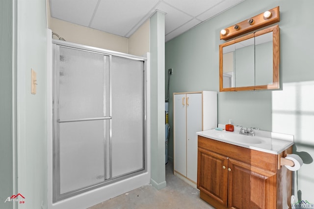 bathroom featuring concrete floors, a drop ceiling, an enclosed shower, and vanity