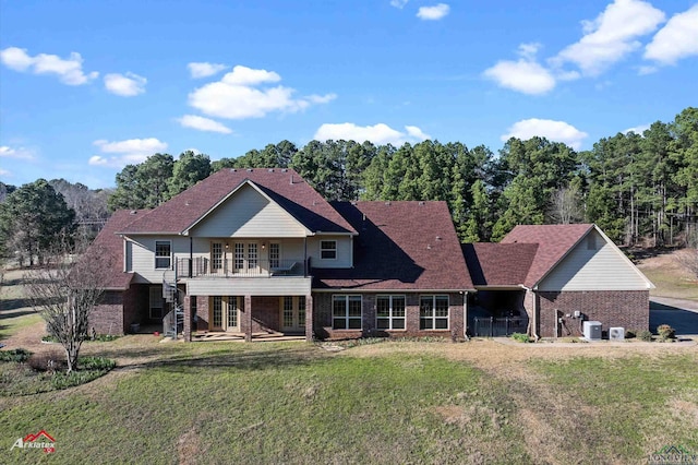 rear view of property with a lawn and a balcony