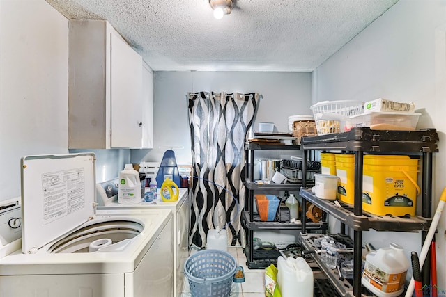 laundry room with washing machine and clothes dryer, cabinets, and a textured ceiling