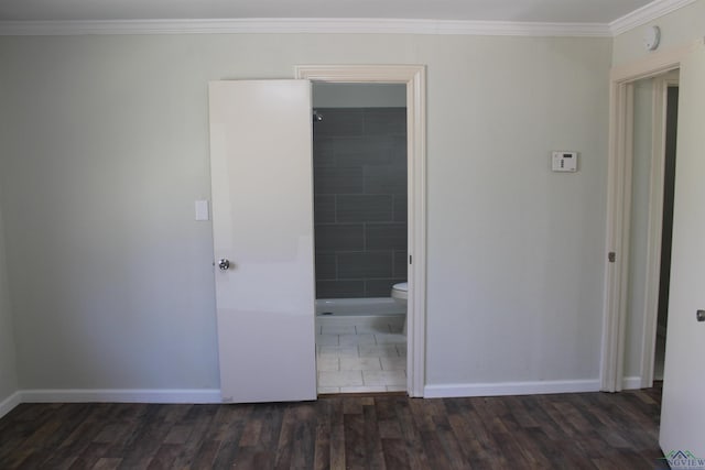 unfurnished bedroom with baseboards, dark wood-style flooring, ensuite bathroom, and crown molding