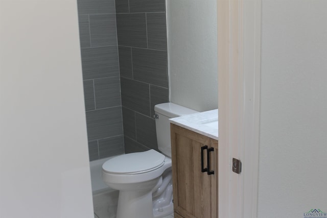 bathroom with toilet, a tile shower, and vanity