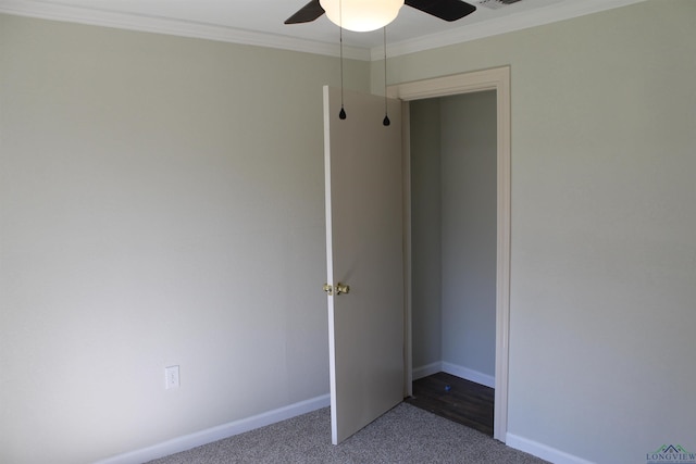 unfurnished bedroom with baseboards, visible vents, a ceiling fan, ornamental molding, and dark colored carpet