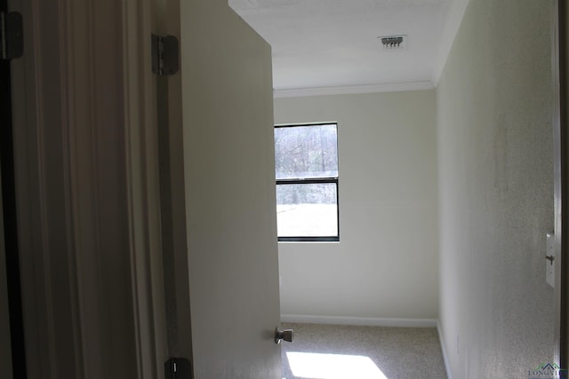 carpeted spare room with ornamental molding, visible vents, and baseboards