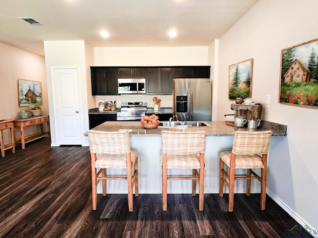 1121 Mission Creek Dr, Longview, TX 75601 - kitchen with stainless steel appliances, dark wood finished floors, a breakfast bar area, a peninsula, and light stone countertops