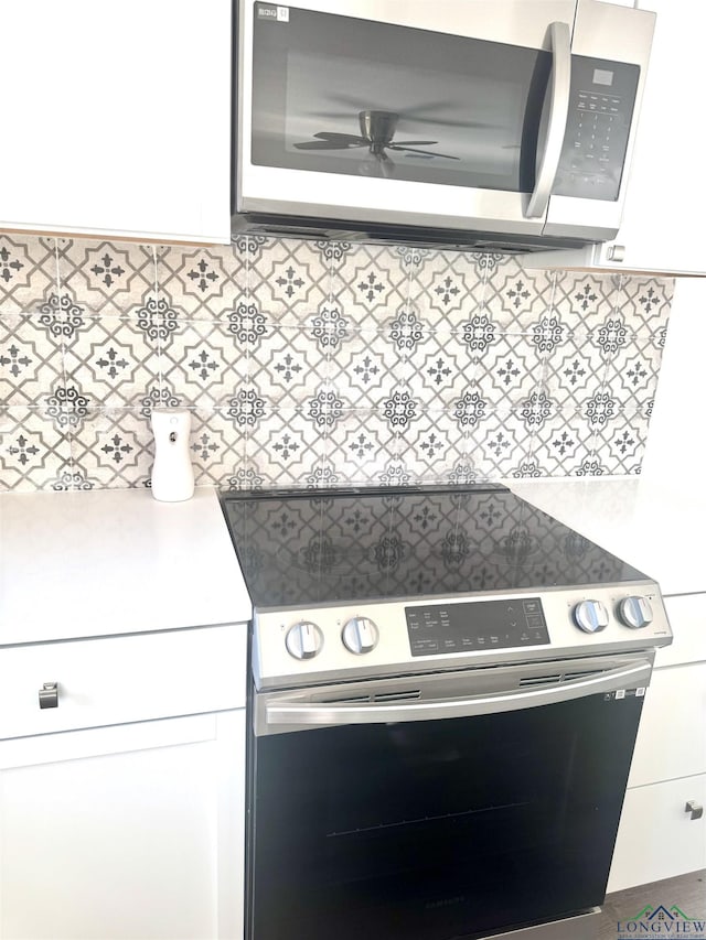 kitchen with appliances with stainless steel finishes, tasteful backsplash, and white cabinetry