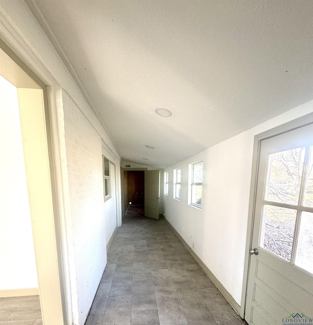 hall with a textured ceiling and vaulted ceiling