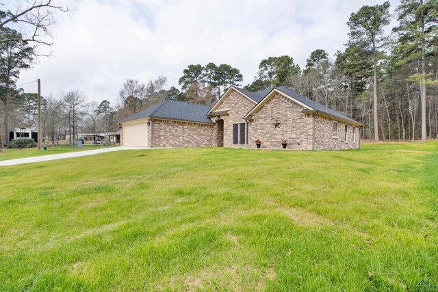 view of front facade with an attached garage, driveway, a front lawn, and brick siding