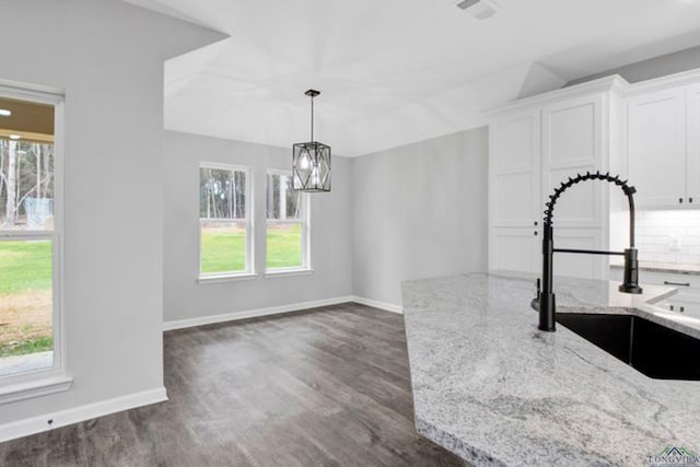 kitchen featuring light stone counters, dark wood-type flooring, sink, and white cabinets