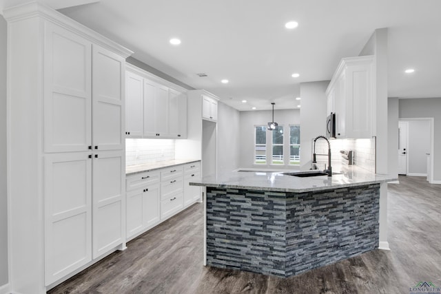 kitchen with white cabinets, a sink, and light stone countertops