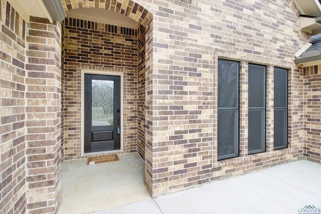 view of exterior entry featuring brick siding