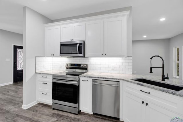 kitchen featuring sink, white cabinetry, stainless steel appliances, dark hardwood / wood-style floors, and light stone countertops