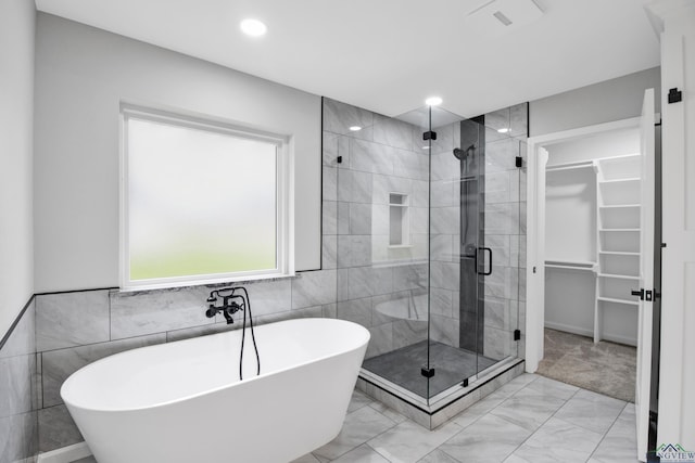 full bath featuring a stall shower, marble finish floor, a spacious closet, a freestanding bath, and recessed lighting