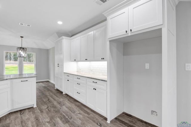 kitchen featuring white cabinetry, decorative backsplash, dark hardwood / wood-style flooring, and light stone countertops