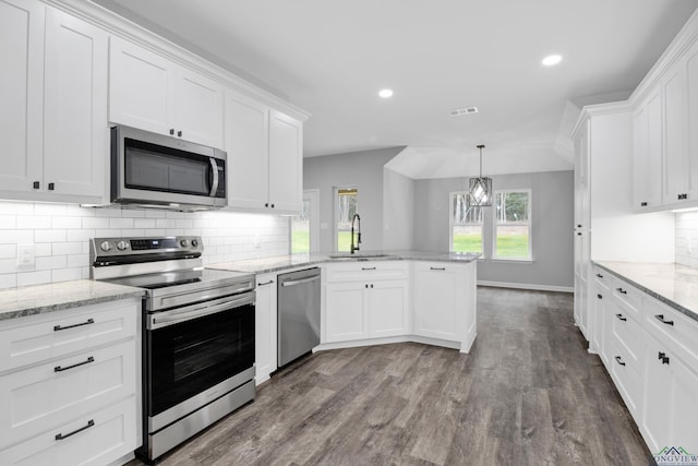 kitchen with stainless steel appliances, a peninsula, wood finished floors, a sink, and white cabinets