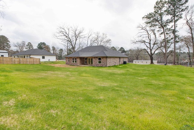 rear view of house with a yard and fence