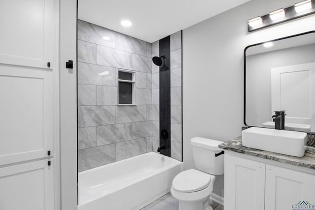 full bathroom featuring tiled shower / bath, vanity, and toilet