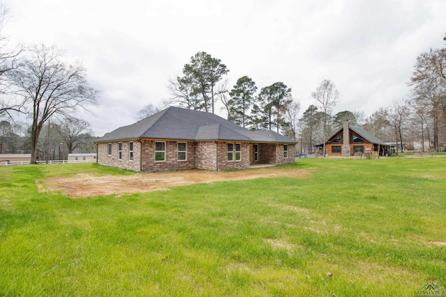 rear view of property with brick siding, a yard, and driveway