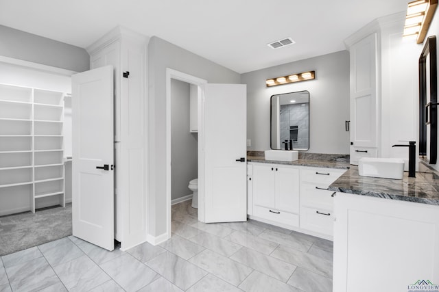 full bathroom featuring visible vents, a spacious closet, toilet, vanity, and baseboards