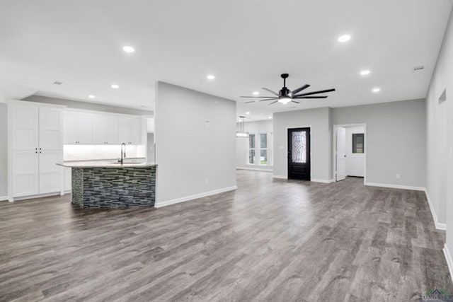 unfurnished living room with ceiling fan, sink, and hardwood / wood-style floors