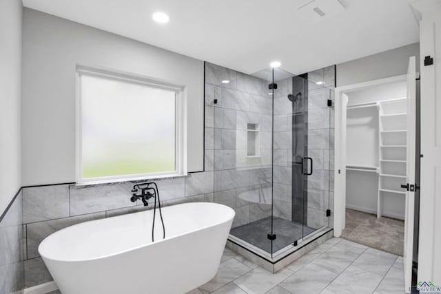 bathroom featuring tile walls and separate shower and tub