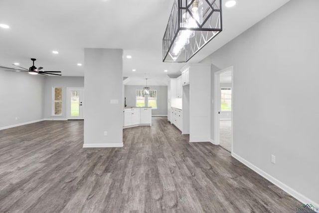 unfurnished living room featuring ceiling fan with notable chandelier and hardwood / wood-style floors