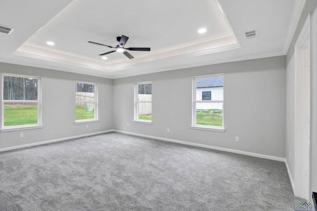 carpeted empty room with a raised ceiling, ornamental molding, and ceiling fan