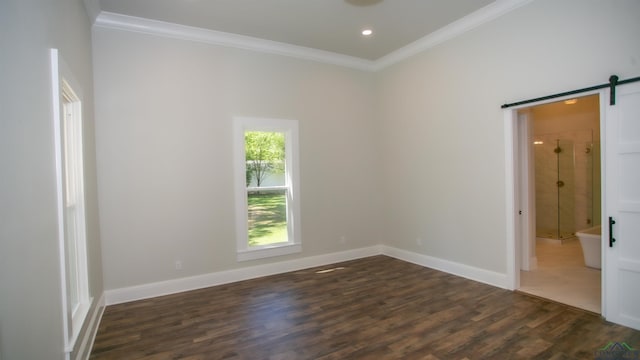 spare room featuring a barn door, dark wood-type flooring, and ornamental molding