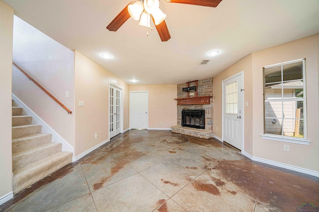 unfurnished living room featuring stairs, ceiling fan, a stone fireplace, baseboards, and visible vents