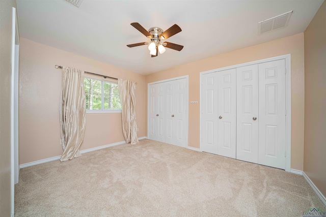 unfurnished bedroom with visible vents, two closets, carpet, and baseboards