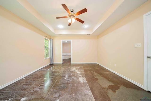 unfurnished bedroom featuring a raised ceiling, recessed lighting, concrete flooring, and baseboards