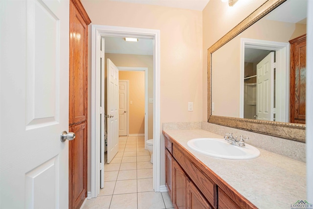 bathroom with toilet, vanity, tile patterned flooring, and baseboards