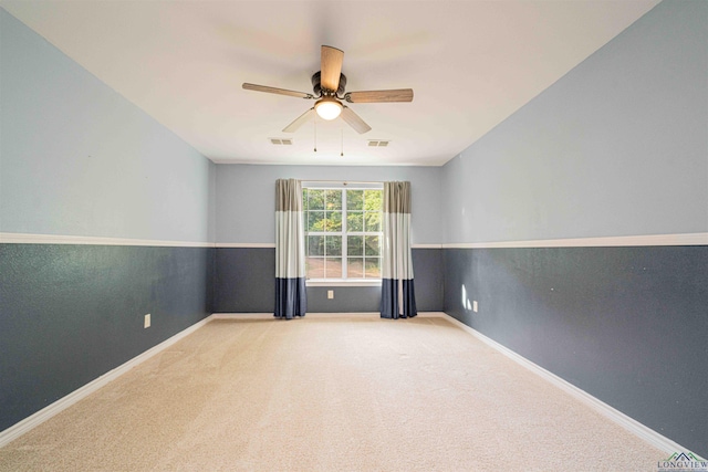carpeted spare room featuring baseboards, visible vents, and a ceiling fan