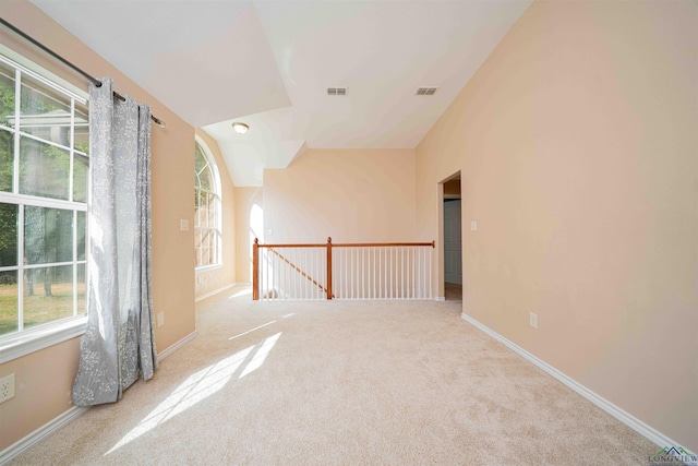 unfurnished room featuring visible vents, a wealth of natural light, and carpet floors