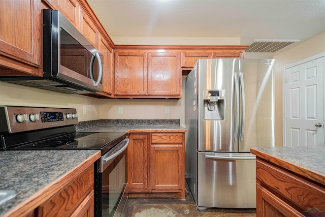 kitchen with dark countertops, visible vents, stainless steel appliances, and brown cabinetry