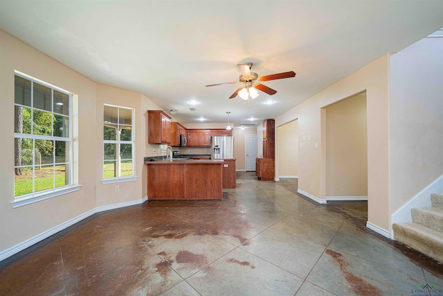 kitchen with appliances with stainless steel finishes, open floor plan, a peninsula, and a sink