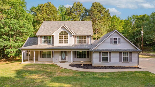 view of front of property featuring a front lawn, a shingled roof, and covered porch