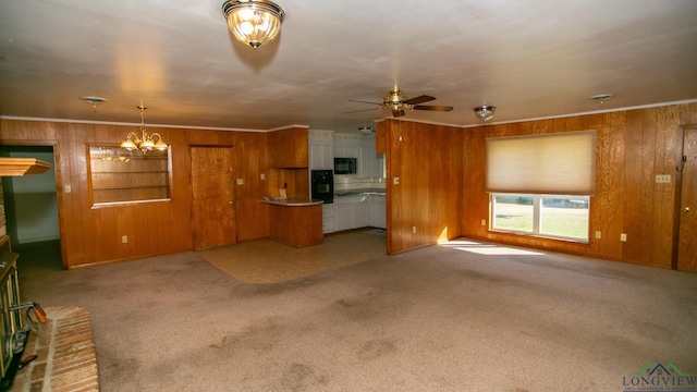 unfurnished living room with ceiling fan with notable chandelier, ornamental molding, and light carpet