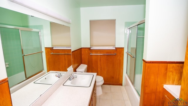 full bathroom featuring wood walls, vanity, enclosed tub / shower combo, and toilet