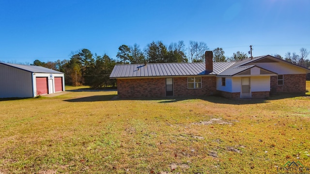 back of house featuring a lawn, a garage, and an outdoor structure