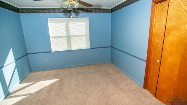 spare room with ceiling fan, light colored carpet, and ornamental molding