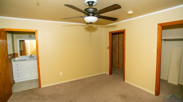 unfurnished bedroom featuring ceiling fan, sink, light carpet, a closet, and ornamental molding