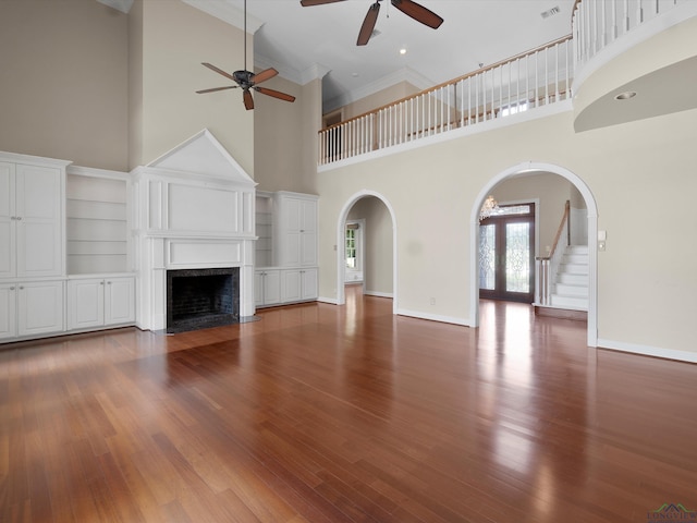 unfurnished living room with ceiling fan, french doors, a high ceiling, wood-type flooring, and ornamental molding