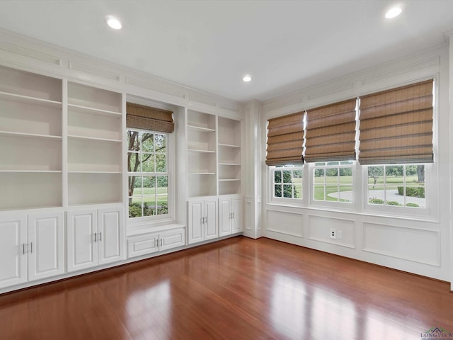 empty room featuring built in shelves and hardwood / wood-style flooring