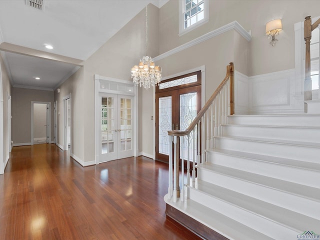 entryway with french doors, dark hardwood / wood-style flooring, an inviting chandelier, and ornamental molding