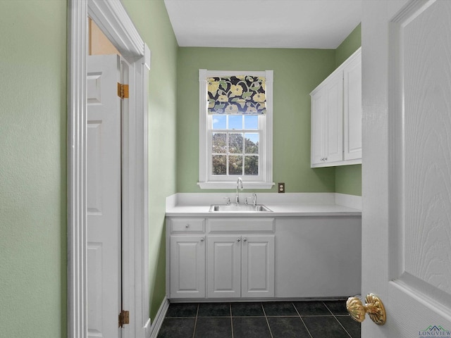 laundry area featuring sink and dark tile patterned floors