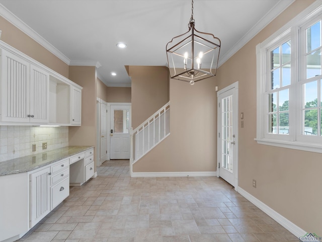 kitchen featuring light stone countertops, tasteful backsplash, crown molding, white cabinetry, and hanging light fixtures