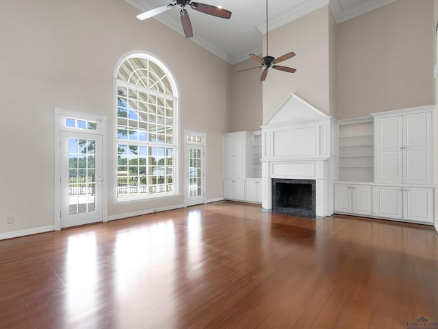 unfurnished living room featuring hardwood / wood-style floors, a towering ceiling, ceiling fan, and ornamental molding